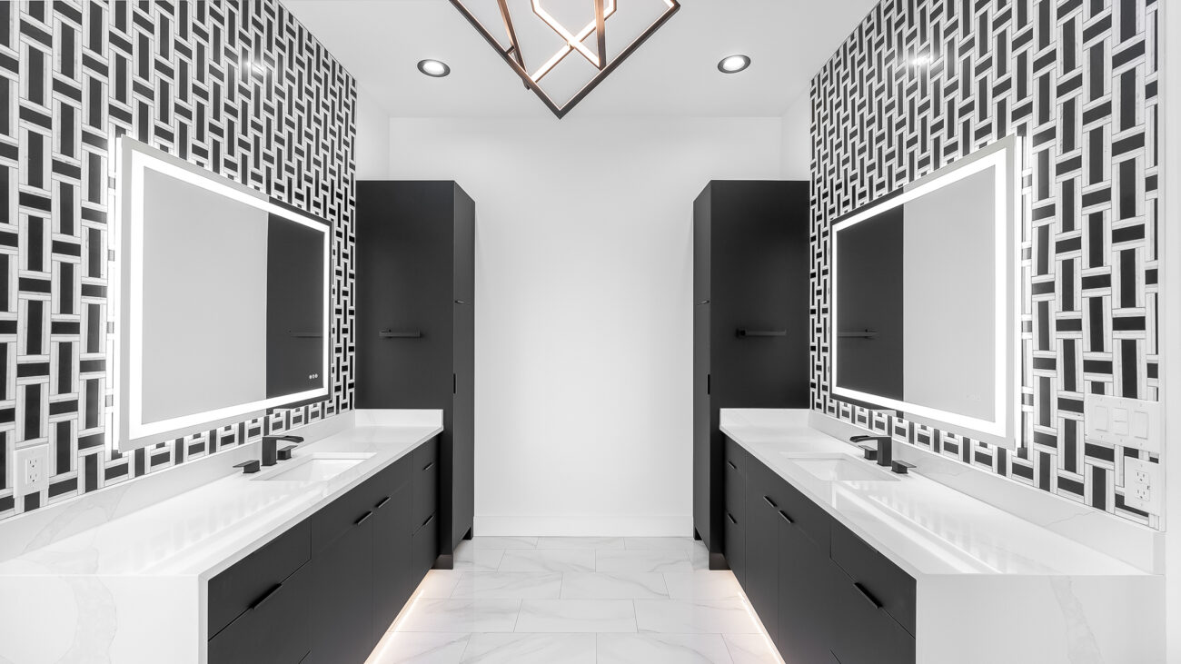 Modern black and white bathroom with matching vanities and bold geometric tile backsplash