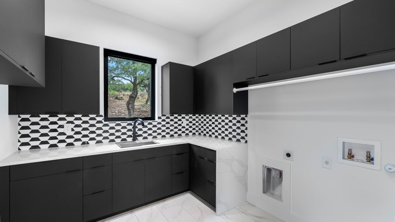 Modern Laundry room with black cabinets and bold geometric tile backsplash